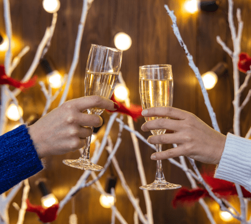 A man and woman celebrating the festive season with a glass of bubbly in either hand. Photo by Artem Kniaz on Unsplash.