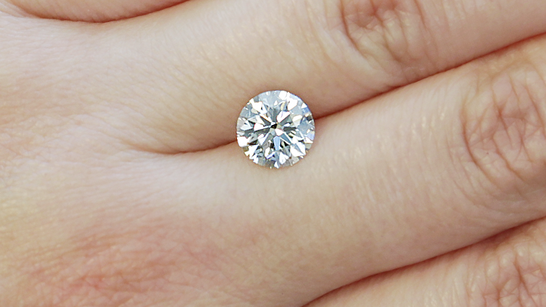 Loose diamond resting on a hand, high quality cut Whiteflash diamond.