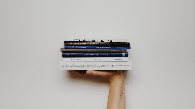 Person holding stack of books - Photo by Thought Catalog on Unsplash
