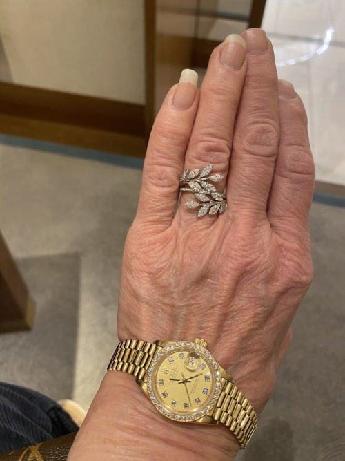 A hand with a stunning vine inspired Tiffany ring and a gold watch at the wrist