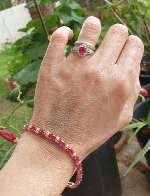 a hand with a ruby and diamond tennis bracelet and a diamond and ruby ring