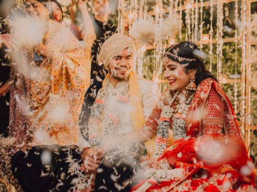 Photo from Indain Wedding couple featured in The Big Day on Netflix. They are smiling and it appears that they are in a confetti shower.