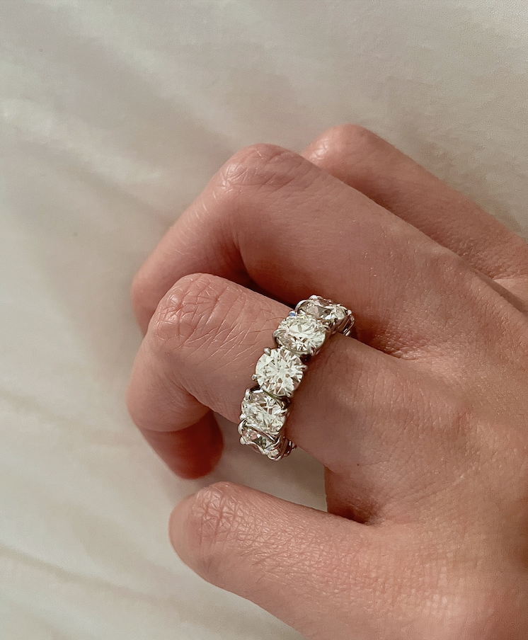 A hand on a white fabric background, fingers slightly curled under. 