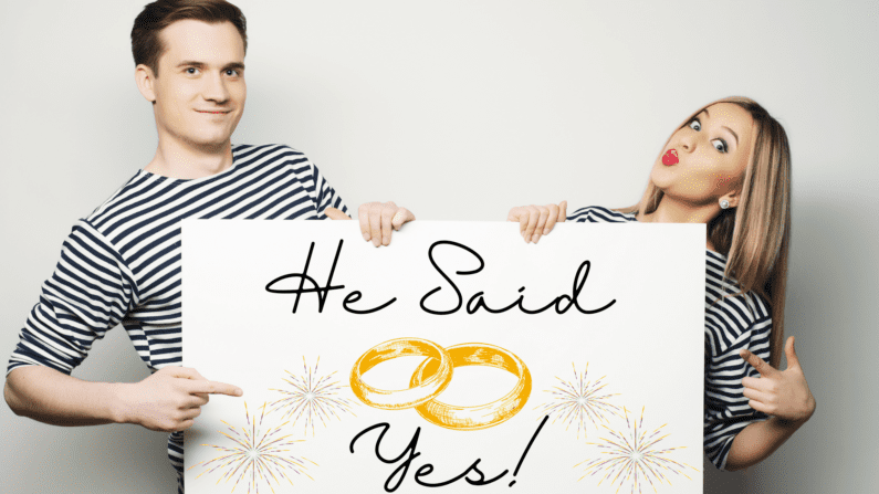 brunette man and blonde woman, both in white and black striped shirts holding a banner that says "He said yes" in a handwriting font, with golden fireworks and 2 gold rings illustrated on the banner.