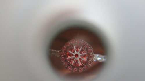A scope overhead shot of a diamond in halo with red light reflecting back 
