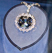 A large blur diamond surrounded by white diamonds on a blue display: The Hope Diamond