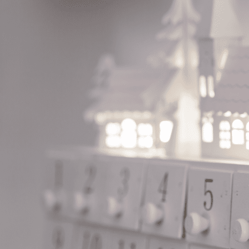 The doors of a wooden advent calendar with a holiday miniature village above it.