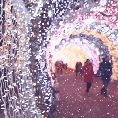 A couple walking through a corridor of christmas lights.