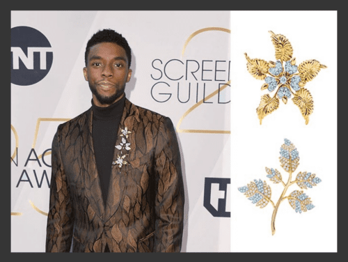Chadwick Boseman in a bronze and black brocade suit, with multiple brooches on his lapel.