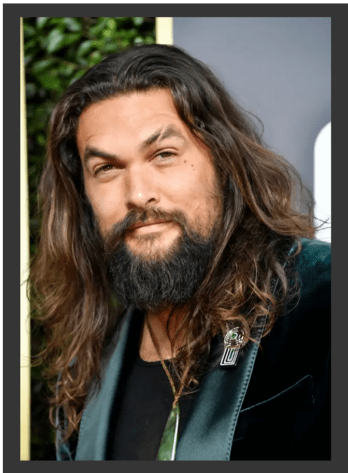 Jason Momoa in a green suit with a emerald and diamond brooch on his lapel.
