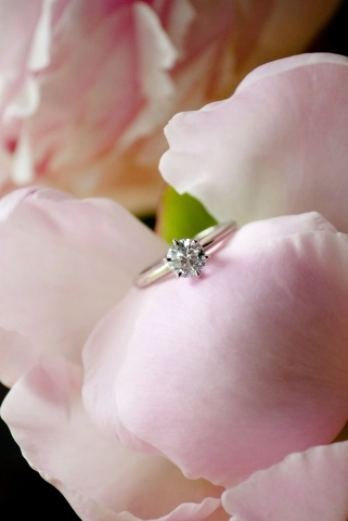 A pink peony with a diamond ring sitting within the petals.
