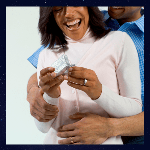 a man and woman embraced opening a ring box.