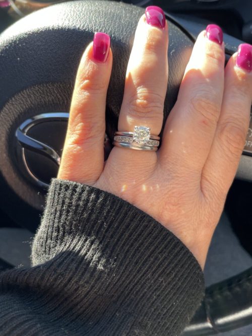 Diamond ring on a hand with lovely painted nails , against a steering wheel. 