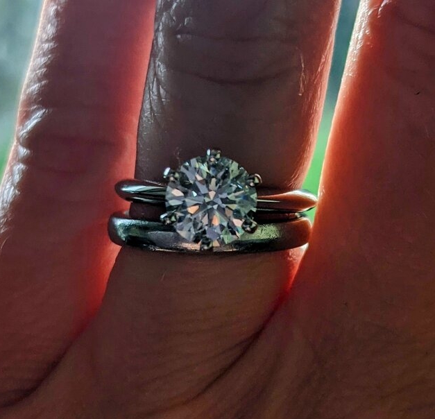Diamond wedding set with large round diamond on a shadowy hand.