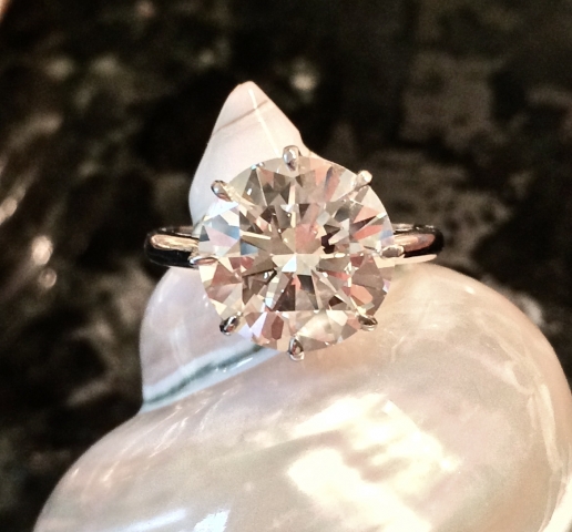 Large round diamond solitaire sitting on a white nacred shell.