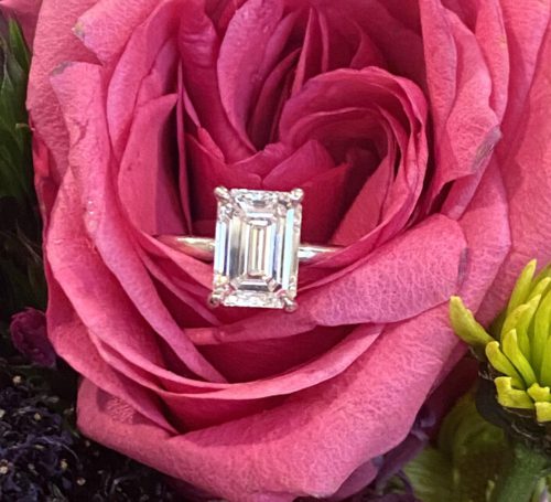 Emerald cut diamond solitaire in a dark pink rose blossom. 