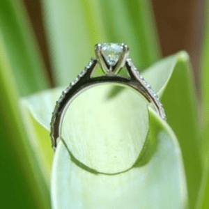 Diamond solitaire ring with a plant bloom threaded through it. 