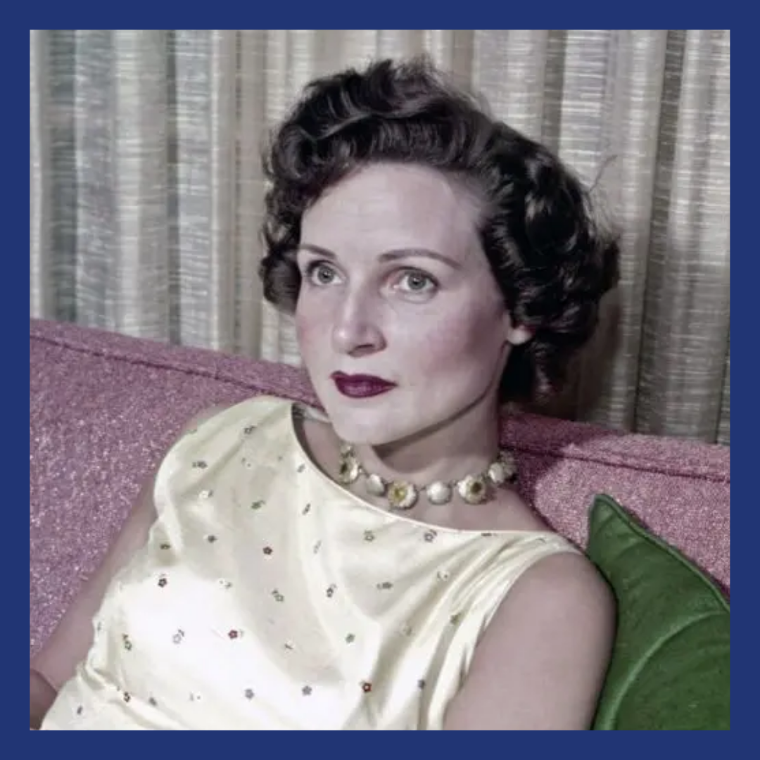 A younger woman from the 50's, in a sleeveless dress and pearls. Shorter curly dark hair.