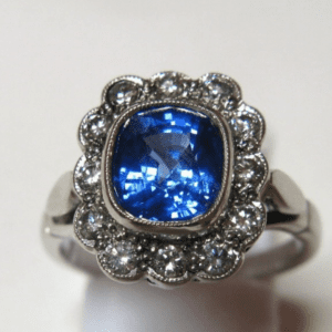 Ring with sapphire cushion in center and halo of diamonds.