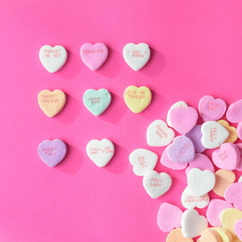 Pink background with conversation hearts on it.