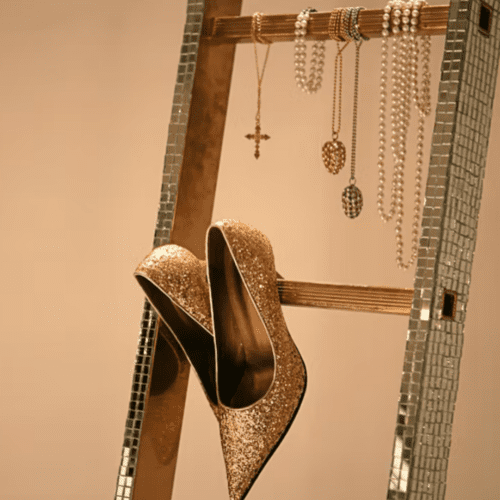 A silver ladder with gold jewelry and shoes hanging from it's rungs.