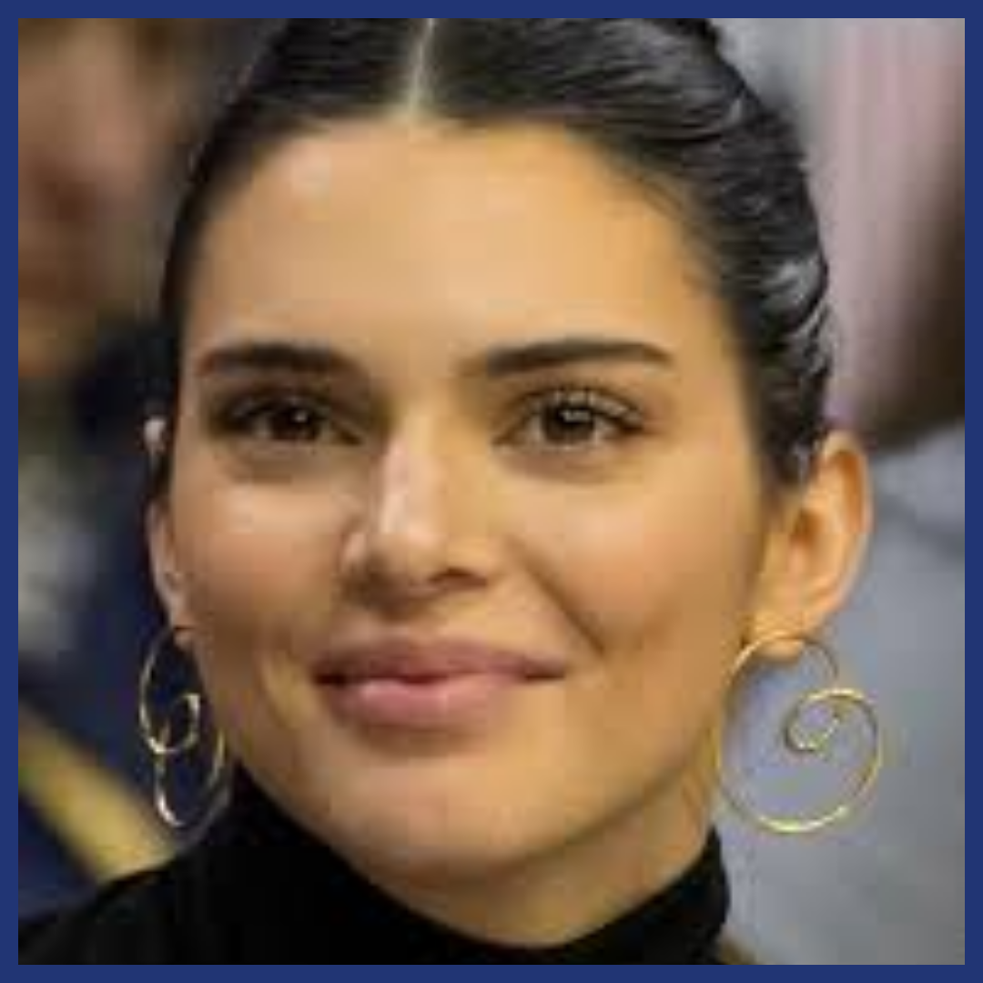 Woman smiling at viewer, dark bun, diamond face shape.