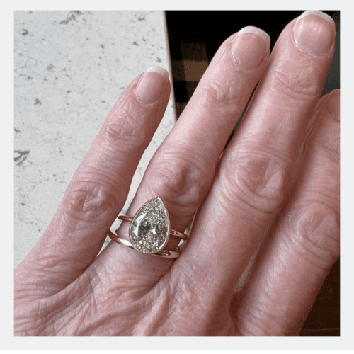 Pear shaped diamond in bezel ring on older feminine caucasian hand.