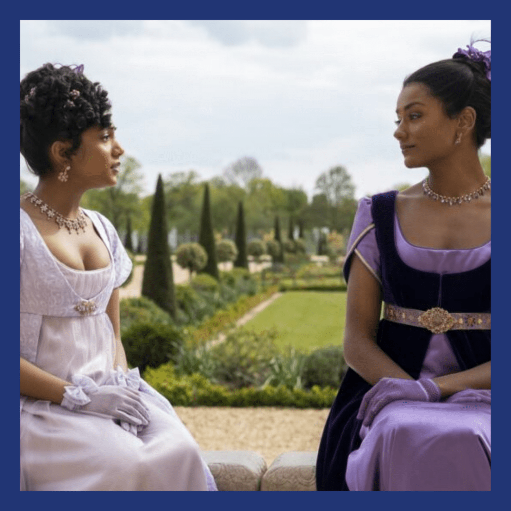 2 light brown women talking in a garden.