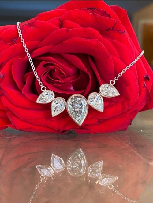 five pear cut diamond pendant on a red rose