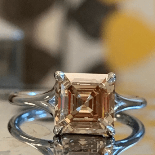 Light brown/yellow diamond ring on a reflective surface.