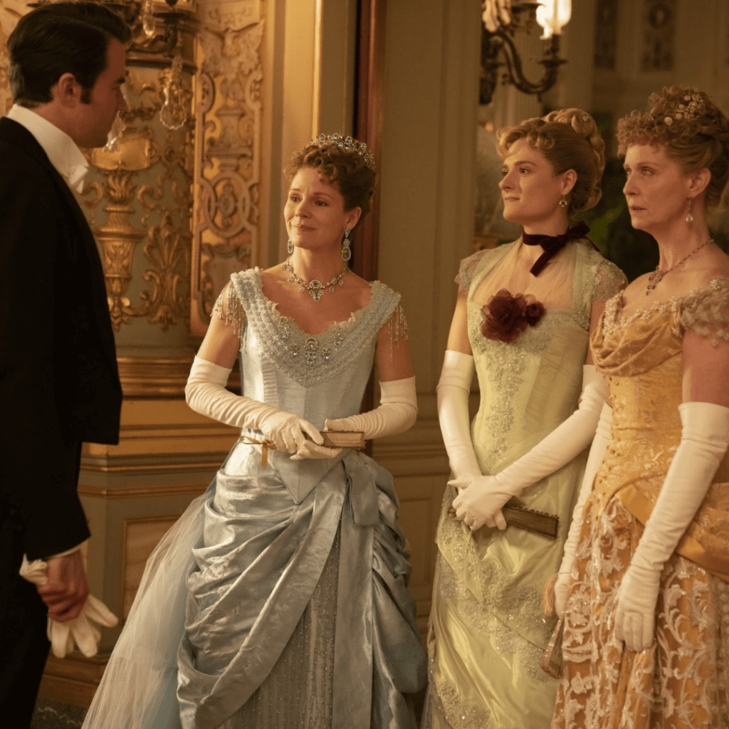 Three women and one man in Gilded Age costumes