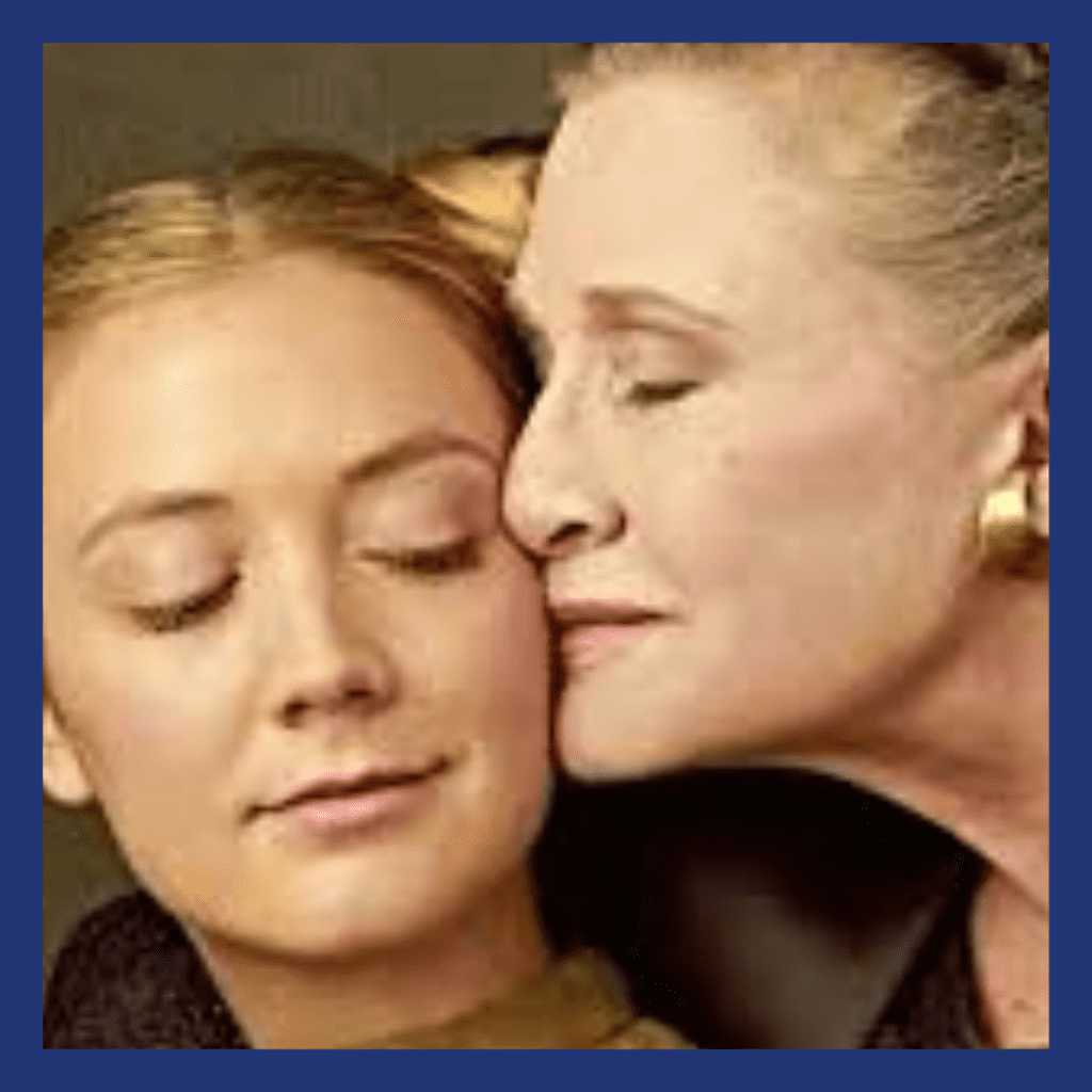 An older woman embracing a younger woman, both have their eyes closed. (Mother/Daughter)