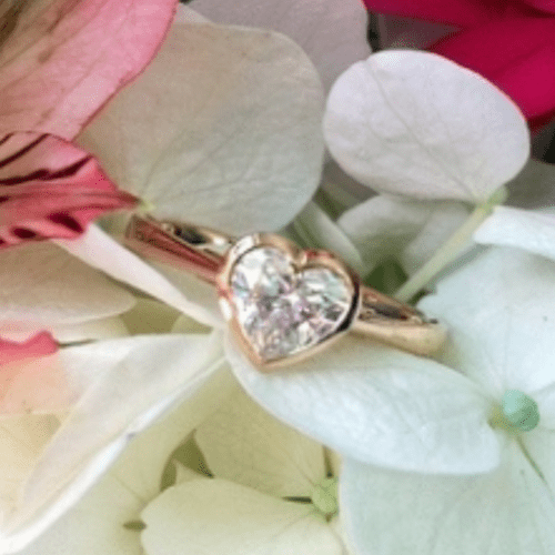 Heart shaped diamond ring on flowers.