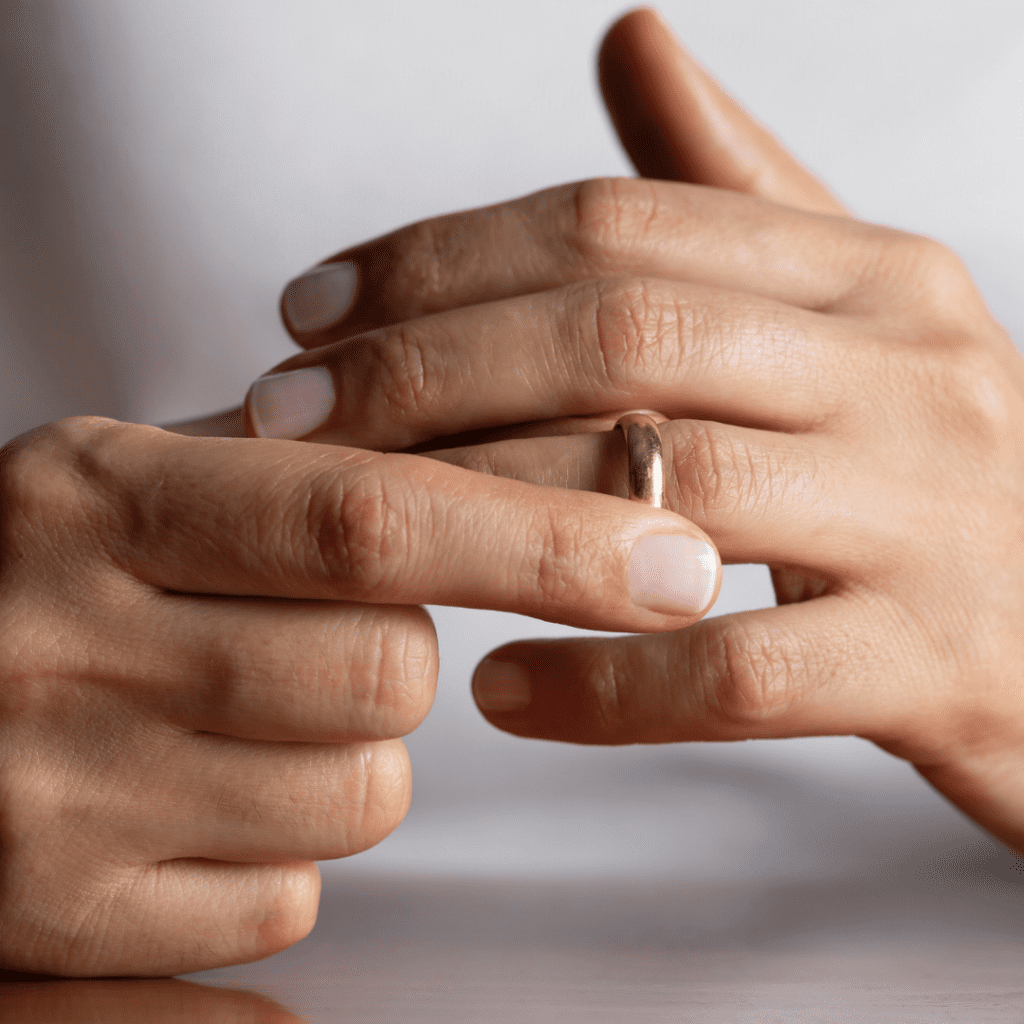 A close up of hands removing a ring from their finger.