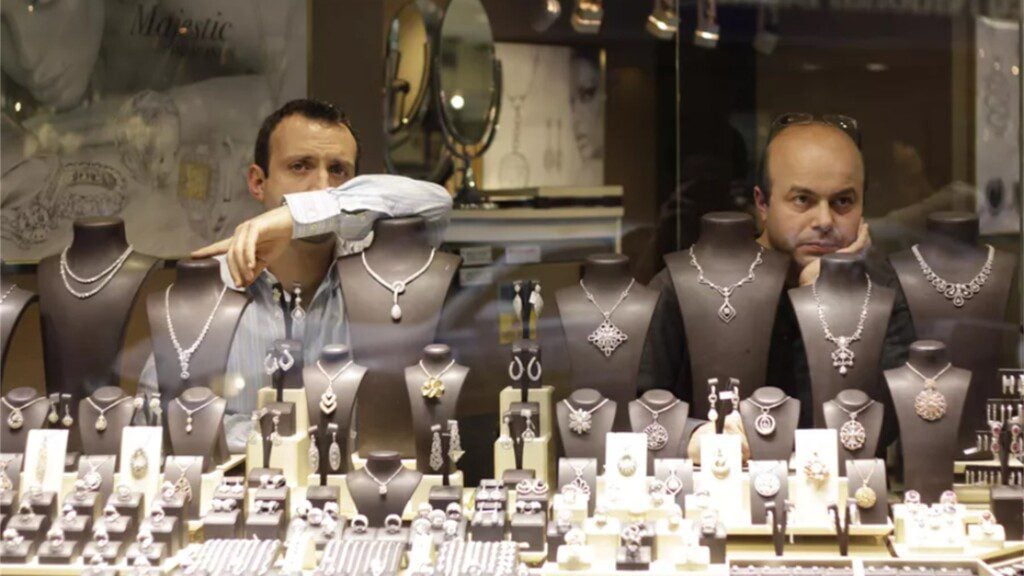 Two men inside a jewellery shop, displaying through their window the wide variety of diamond jewellery they have to offer