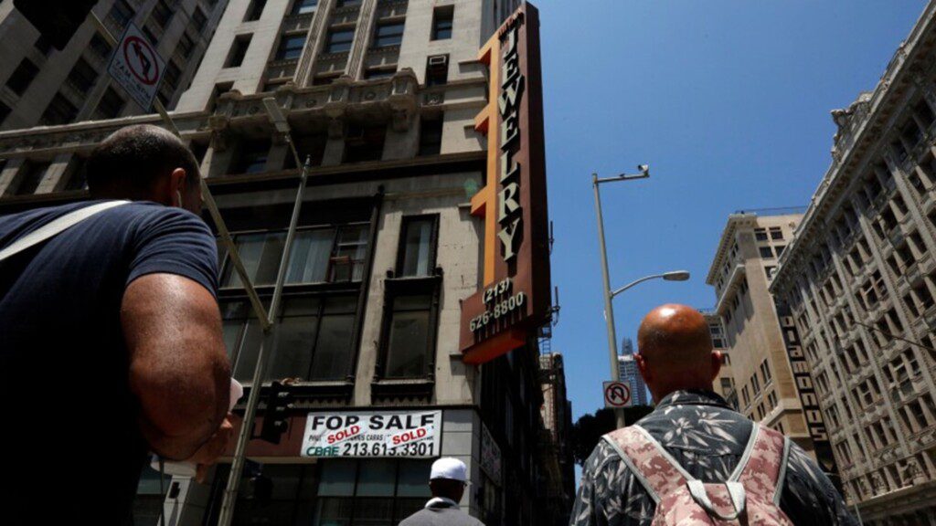 Two men on a crossing, looking up to a jewellery advertisement in Los Angeles