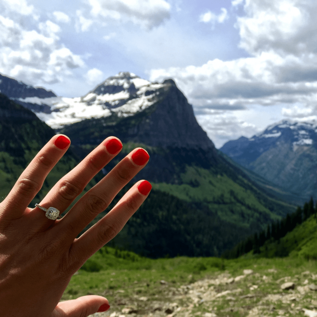 mountain range with hand in forefront with engagement ring