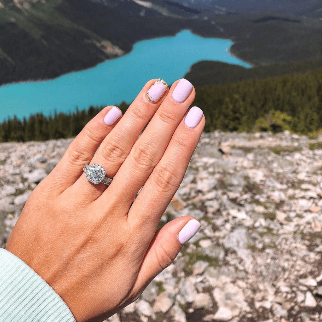 mountain range with hand in forefront with engagement ring