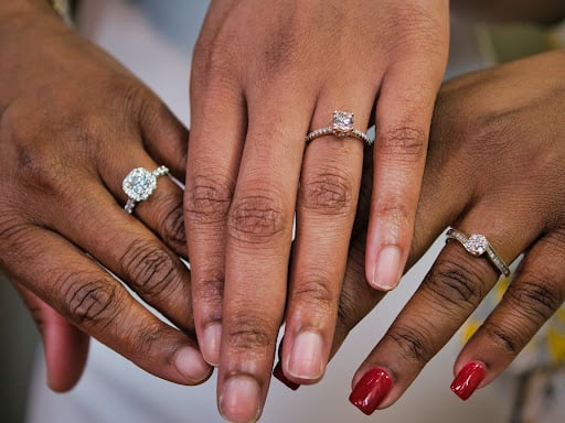 Three women with their hands together, showing their engagement rings off