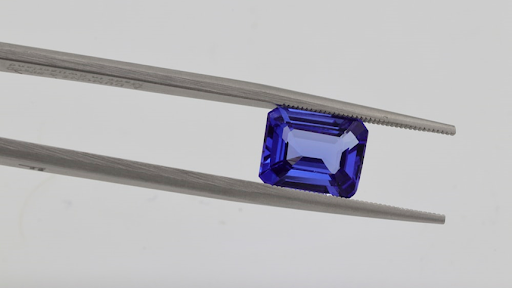 Sapphire blue gemstone in between jeweller's tweezers