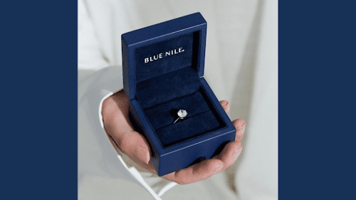 Blue Nile blue open ringbox with small diamond engagement ring inside 