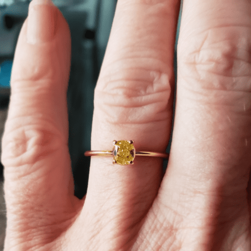 Yellow diamond ring on a hand.