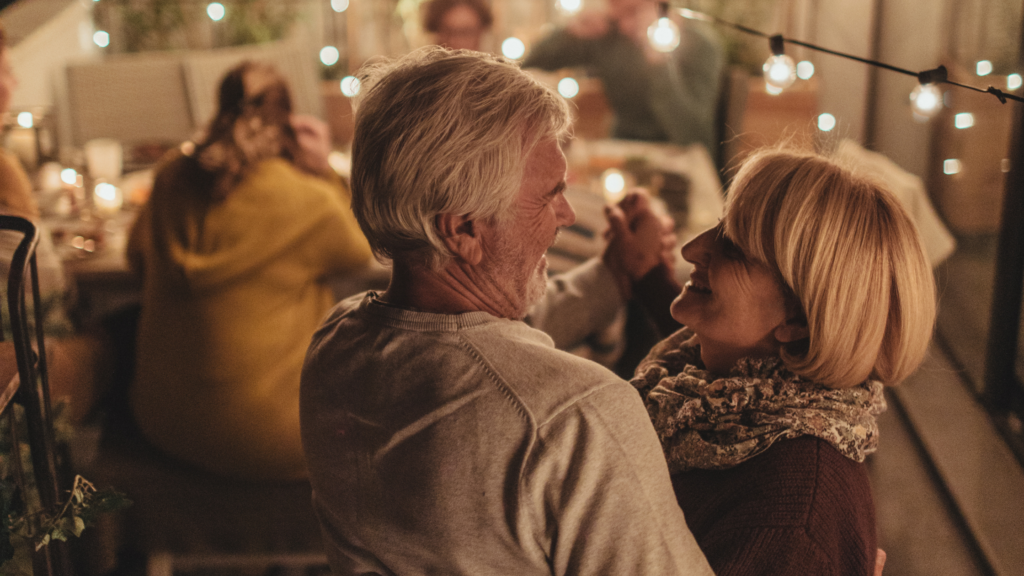 An elderly couple dacing with a party behind them.