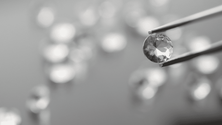 Round cut diamond with other blurred diamonds in background.