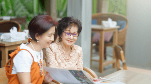 Mother and adult daughter read a menu together.