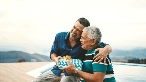 Aging father being gifted by adult son in a side hug