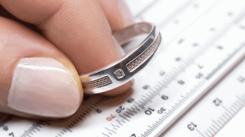 Wedding band photographed over a Ring size chart